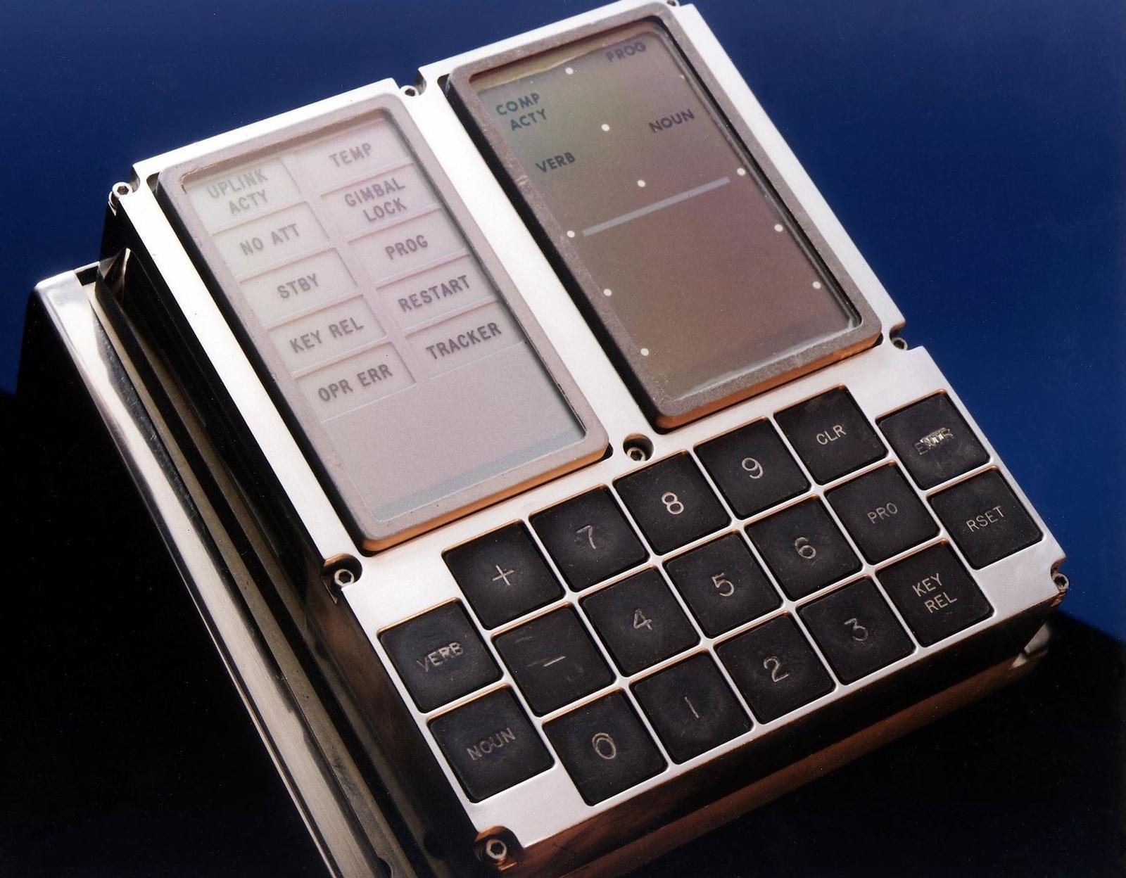 A metal box with two small display panels above a keypad of numbered keys and keys marked VERB, NOUN, CLR, PRO and RSET.